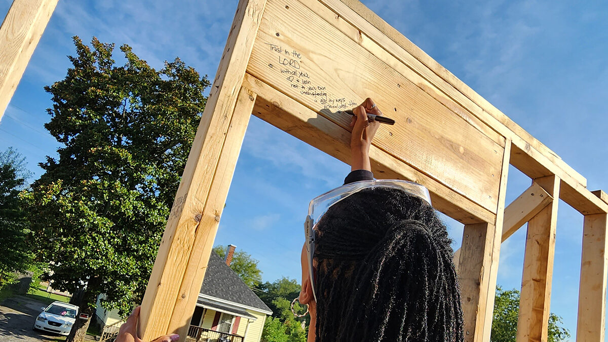 Linda Coltrane writing message on house frame