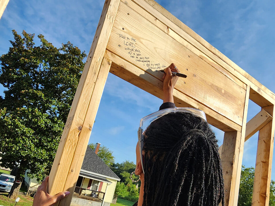 Linda Coltrane writing message on house frame