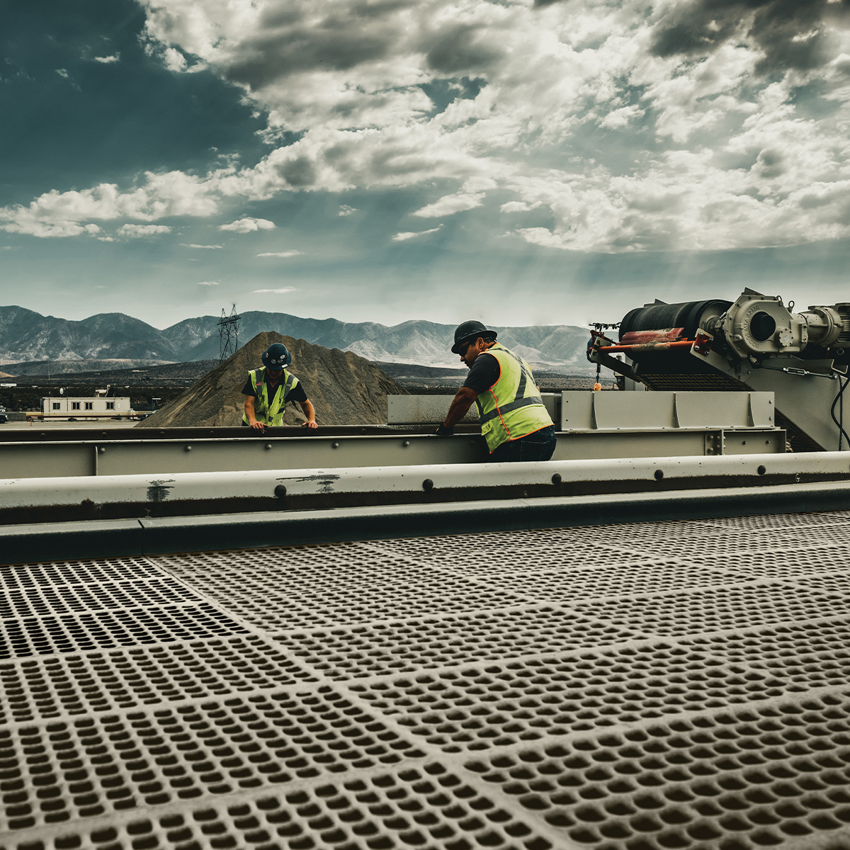 Two workers installing screening media in an industrial facility