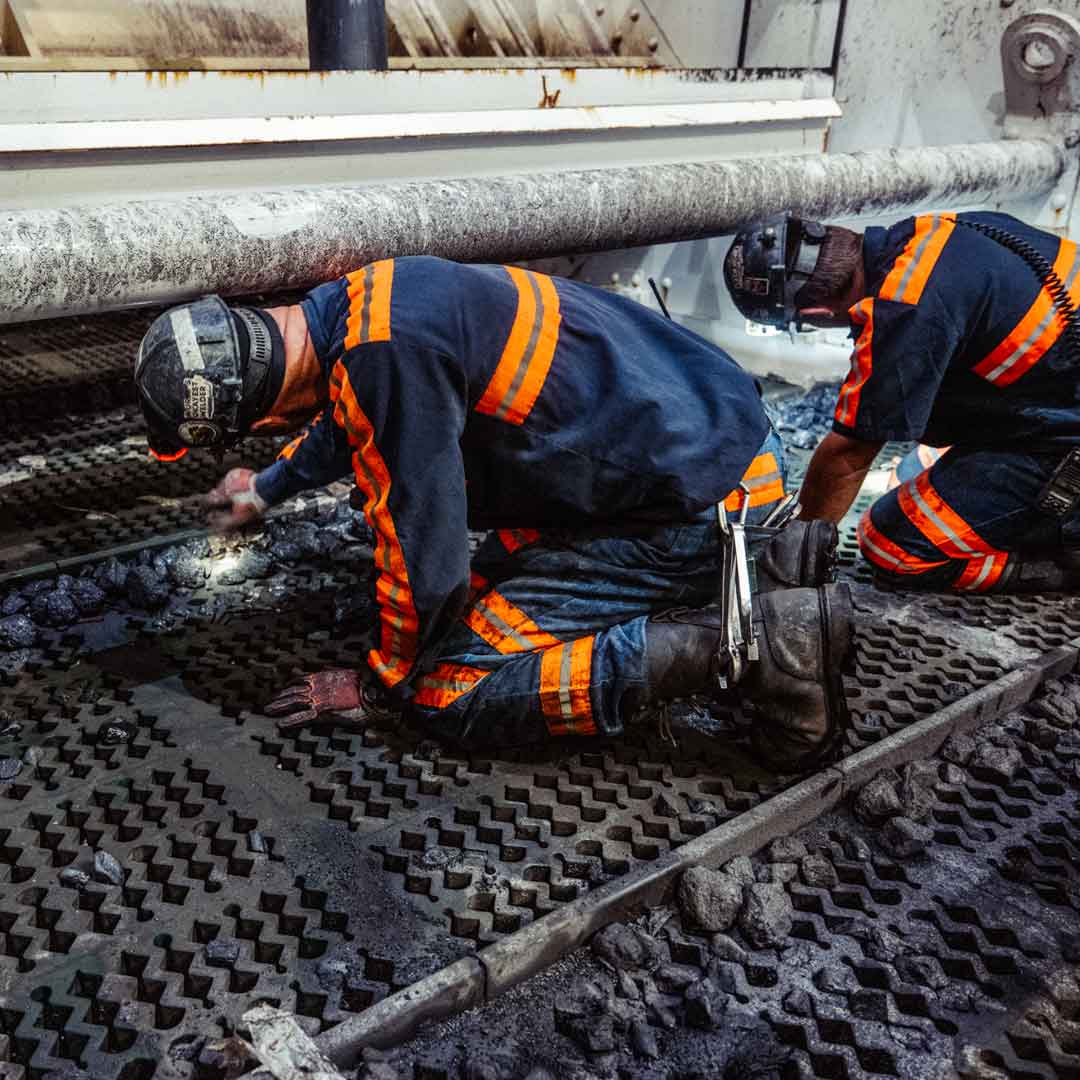 Technicians in a coal mining site installing screening media